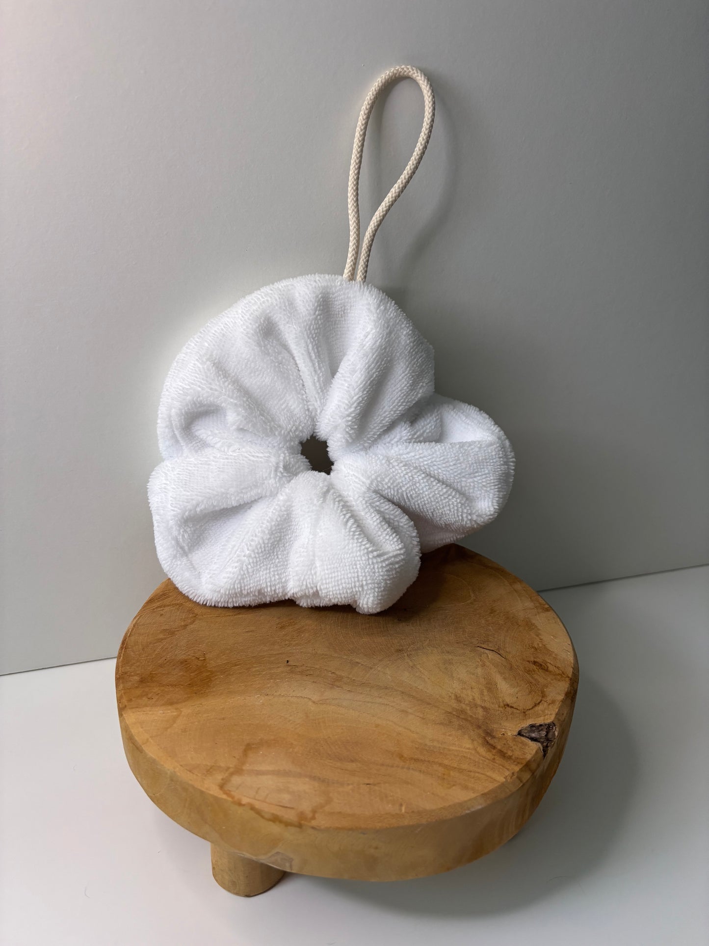 Fleur de douche en éponge de bambou de couleur blanche, posée sur une surface en bois