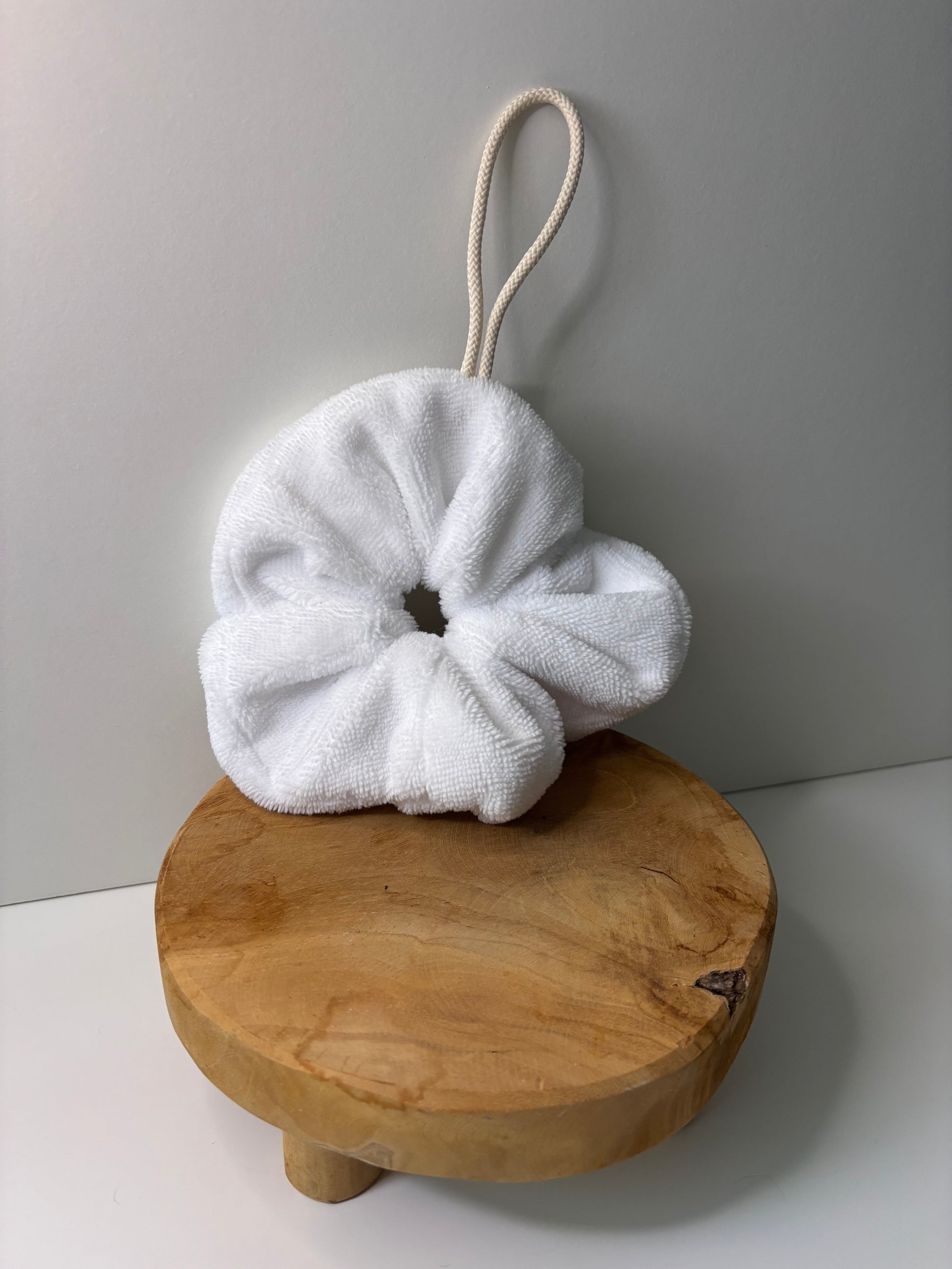 Fleur de douche en éponge de bambou de couleur blanche, posée sur une surface en bois