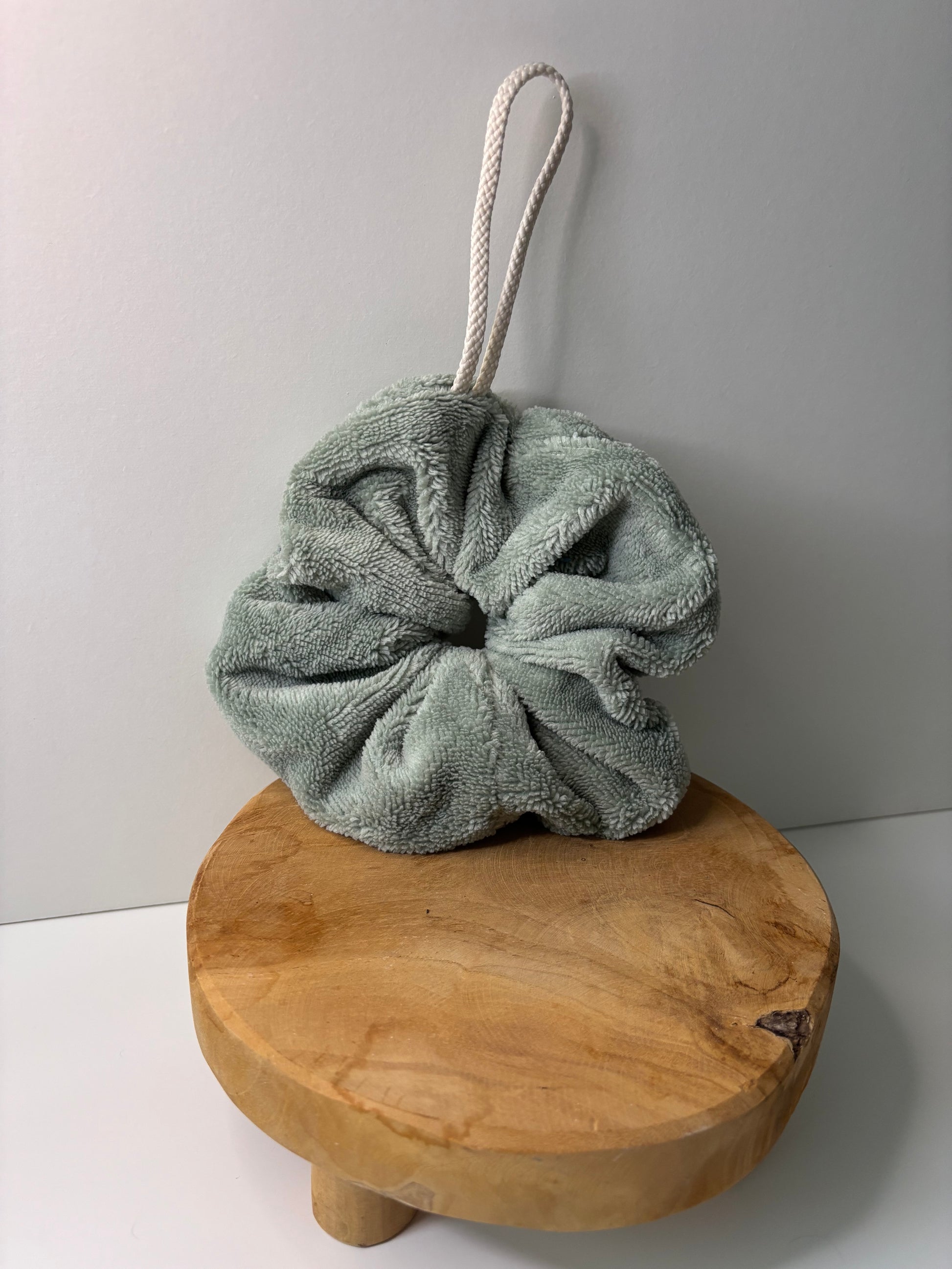 Fleur de douche en éponge de bambou de couleur verte, posée sur une surface en bois