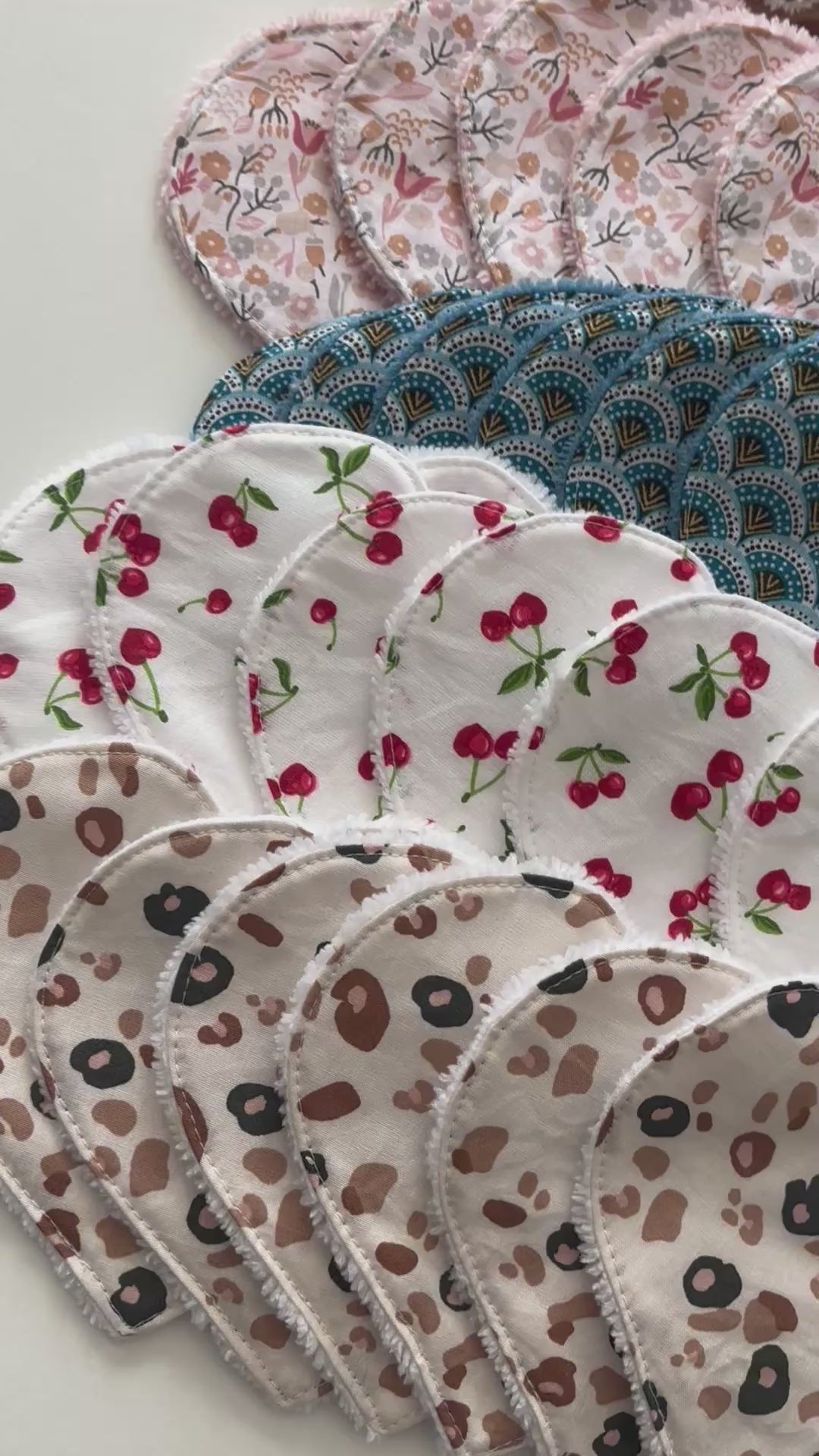 Présentation de plusieurs cotons lavables en forme de cœur – différents motifs (léopard, fleurs, cerises, géométrique).